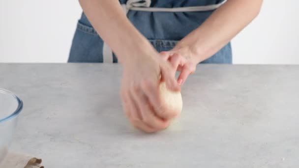 Dłonie kobiet ugniatają ciasto na lekkim stole do pieczenia chleba pszennego. Gotowanie białego chleba w profesjonalnej piekarni z mąki, wody, oleju, soli. — Wideo stockowe
