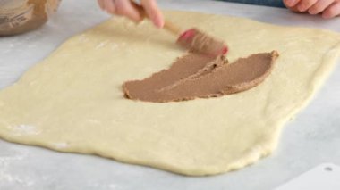 Güzel kadın elleri tarçın ve çikolatalı çörek yapmak için hamuru tarçınlı tereyağına bular. Ekmek ve ekmekler. Maya ekmeği. Süt, tereyağı, un, yumurta ve mayadan yapılmış ekmek..