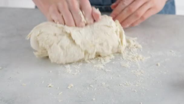 여자 손으로 가벼운 탁자 위에서 밀 빵을 만들기 위해 반죽을 만듭니다. 전문적 인 빵집에서 밀가루, 물, 기름, 소금으로 흰 빵을 요리하는 모습. — 비디오