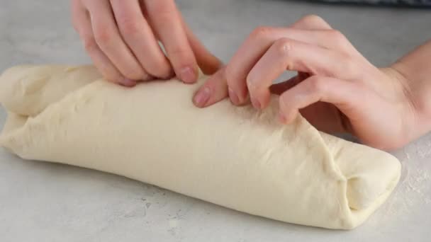 As mãos femininas enrolam a massa em um rolo em uma mesa leve para fazer pão de trigo. Preparamos o pão branco em uma padaria profissional da farinha, água, óleo, sal. — Vídeo de Stock