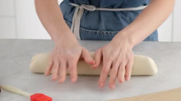 Les mains de la femme placent la pâte sur une plaque à pâtisserie sur une table lumineuse pour faire du pain de blé. Nous préparons du pain blanc dans une boulangerie professionnelle à partir de farine, eau, huile, sel. — Video