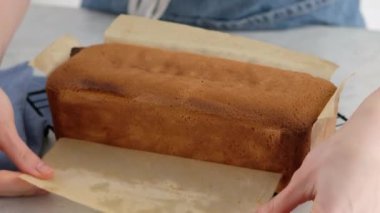 Dişi eller dikdörtgen bir kek ve kremalı pasta kağıdı çıkarırlar. Pasta şefi ev yapımı bir pasta hazırlıyor. Mutfak, pişirme konsepti. Charlotte kremalı kremalı pandispanya..