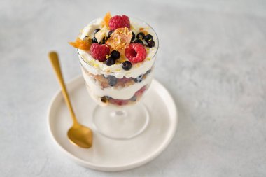 Ahududu, yaban mersini ve kremayla dolu bir bardakta tatlı..