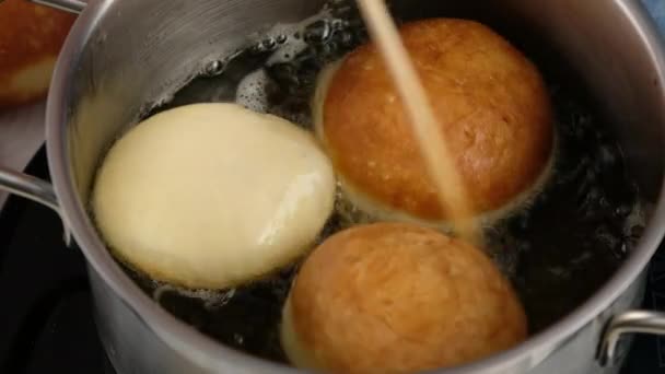 Berliners. Donuts rolantes em óleo. Os donuts fritam-se no óleo vegetal. Deliciosos donuts doces. Fazendo donuts com geléia. — Vídeo de Stock