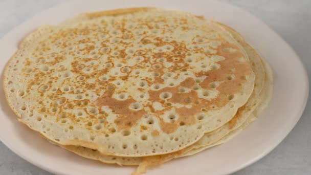 Ponga el panqueque en un plato y engrase con mantequilla. Gran panqueque redondo. El humo de la cocina sube de la tortita. Panqueques con kéfir. Panqueques con agujeros. Semana de tortitas. Tradición rusa. — Vídeos de Stock