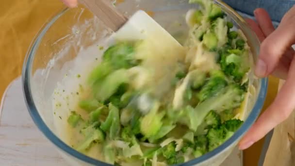 Een close-up. Roer de ingrediënten in een glazen kom om broccoli en kaasfrittat in een bakvorm te maken. Italiaans ontbijt. Gehakte omelet gebakken met groenten en broccoli. Gezond ontbijt. — Stockvideo