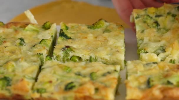 Primer plano del movimiento de la cámara. Las manos de las mujeres colocan una rebanada de frittats de brócoli en un plato. Desayuno italiano. Tortilla picada al horno con verduras y brócoli en un plato de servir. Desayuno saludable. — Vídeos de Stock