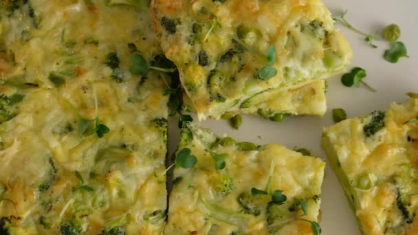 Primer plano del movimiento de la cámara. Frittata con brócoli en un plato. Desayuno italiano. Tortilla picada al horno con verduras y brócoli en un plato de servir. Desayuno saludable. Vista superior. — Vídeo de stock