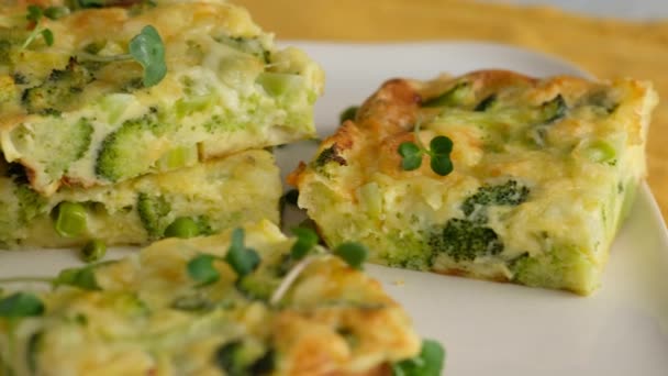 Närbild kamerarörelse. Frittata med broccoli på en tallrik. Italiensk frukost. Bakad hackad omelett med grönsaker och broccoli på en serveringsplatta och lägger den på bordet. Sund frukost. — Stockvideo