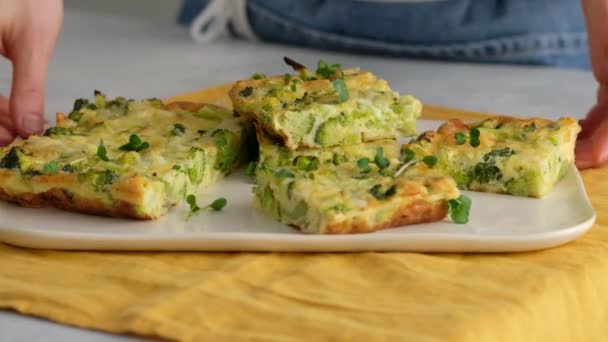 Primer plano. Las manos femeninas ponen brócoli frittata en un plato. Desayuno italiano. Tortilla picada al horno con verduras y brócoli en un plato de servir. Desayuno saludable. — Vídeos de Stock