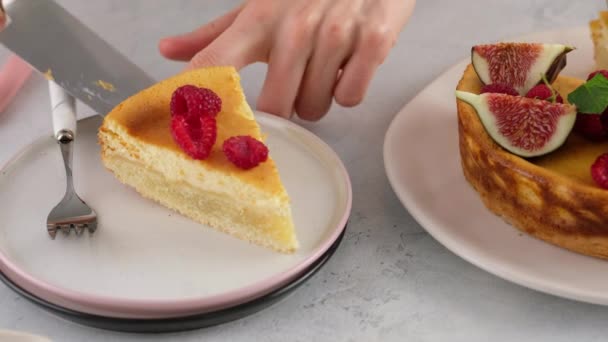Närbild. Kvinnlig hand skära en cheesecake med bär och sätta på en tallrik. Läcker hemlagad ostpaj med saftig fyllning, utsmyckad med bär, hallon, fikon. Vacker dessertpresentation. — Stockvideo
