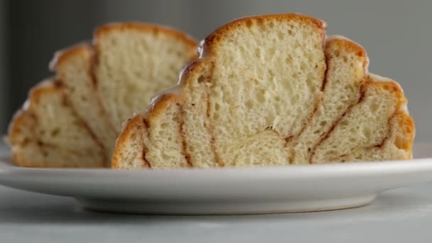 Primer plano de corte de rollos de canela en un plato. Helado de queso crema dulce vertiendo en rollos de canela. Producción de rollos de canela. Productos de panadería. Bollos de canela apetitosos — Vídeo de stock