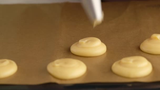 Beim Kochen von Choux oder Profiterolen drücken weibliche Hände den Teig aus der Tüte in Großaufnahme auf ein Backblech. Kochen cremig und Beerenchoux mit Schokolade Craquelin. Vanilleschote — Stockvideo