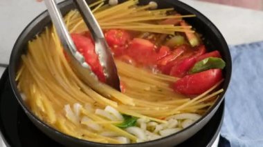 Bir tava pastası. Kadın bir aşçının yakın plan resmi. Bir tava makarna pişiriyor ve içine karıştırıyor..