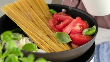 Bir tava pastası. Kadın bir aşçının yakın plan resmi. Bir tava makarna pişiriyor ve içine karıştırıyor..