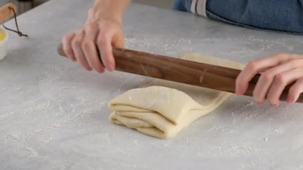 Mooie vrouwelijke handen in een professionele keuken rollen deeg uit voor het maken van brood, pizza en broodjes. Gistbrood. Brood van melk, boter, meel, eieren en gist. — Stockvideo