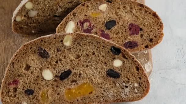 Pohyb kamery. Zavřít. Krásný rustikální žitný chléb leží na dřevěné desce. Chléb z ječného sladu, mouky, soli. Zemgalský chléb se sušeným ovocem. pohled shora. — Stock video