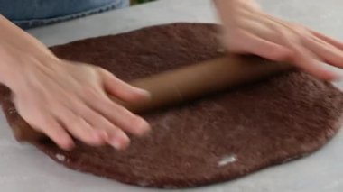 Kadın eli çikolatalı kurabiye yapmak için çikolata hamuru serer. Çikolatalı kurabiye ve zencefilli ekmek yapıyorum. Kurabiye hamuru. yakın plan.
