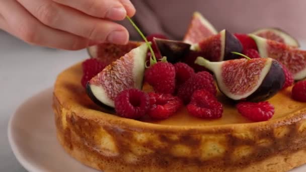 Close-up. Female hands decorate the cake. Delicious homemade cottage cheese pie with juicy filling, decorated with berries, raspberries, figs and mint. Beautiful dessert presentation. — Stock Video