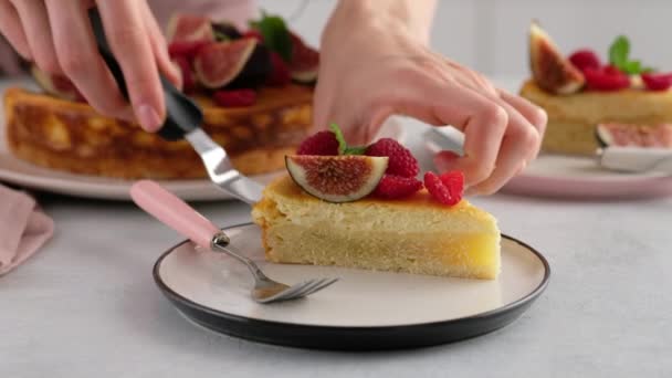 Närbild. Kvinnlig hand skära en cheesecake med bär och sätta på en tallrik. Läcker hemlagad ostpaj med saftig fyllning, utsmyckad med bär, hallon, fikon. Vacker dessertpresentation. — Stockvideo
