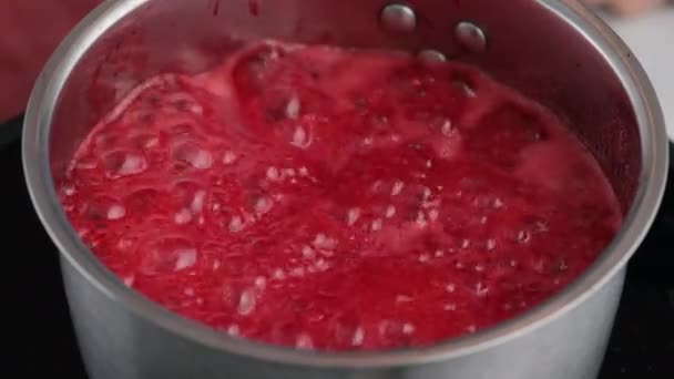 Robię dżem do napełniania pączków. Gotowanie sosu jagodowego. Gotujący się czerwony dżem. Dżem gotuje się w rondlu.. — Wideo stockowe