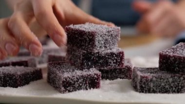 Kadın eli, ev yapımı marmelatı tabağa şeker serpiyor. Şekerli koyu kırmızı marmelat. Şekerli ev yapımı marmelat..