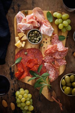 Sosisli, jambonlu, jambonlu, jambonlu, jambonlu, pastırmalı, zeytinli, adaçaylı. Ahşap tepside aperatif. Uzayı kopyala Üst görünüm