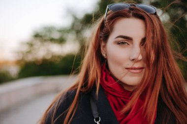 Yeşil gözleri ve geniş kaşları kameraya bakarak ve gülümseyen güzel kadın. Sıcak giysiler giymiş modeli.