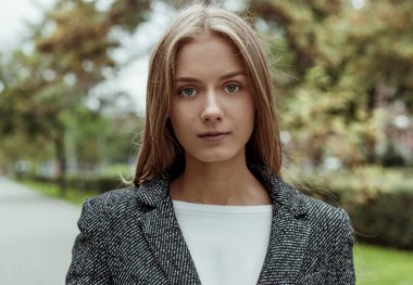 Güzel, sarışın, genç bir manken. Gri, kalın bir palto giymiş. Şehir Bulvarı 'nda kameraya poz veriyor.