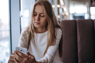 Mutsuz genç bir kadın telefonla mesaj atıyor.