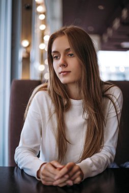 Mutsuz, güzel bir kadın kanepede tek başına oturuyor.