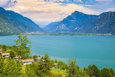 Idro İtalya Gölü 'nün güzel manzarası. Evler, ön plandaki küçük köy ve arka plandaki mavi su ve dağlar.. 