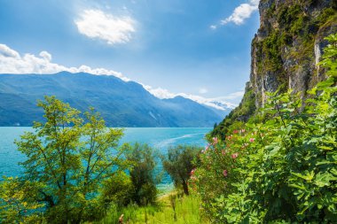 Güzel bir yaz gününde İtalya 'nın Garda Gölü' ndeki doğa manzarası. Mavi su, kayalar, dağlar, güneş ışığı ve berrak gökyüzü.