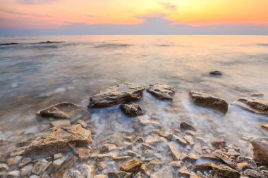 Adriyatik Denizi kıyısında Istria Hırvatistan 'da kayaları olan bir plajda renkli bir gün batımı