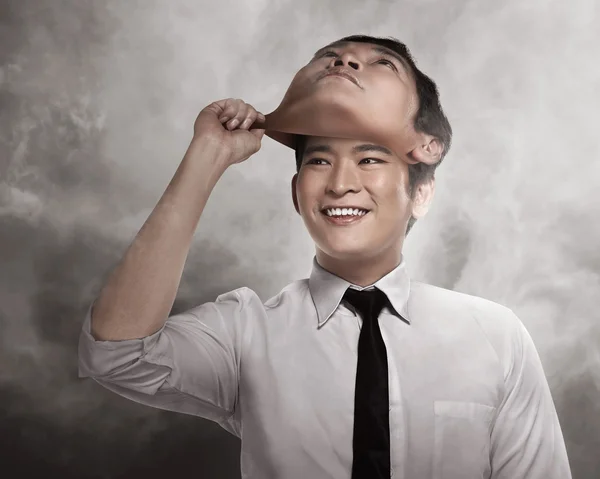 Бизнесмен снимает маску с лица — стоковое фото