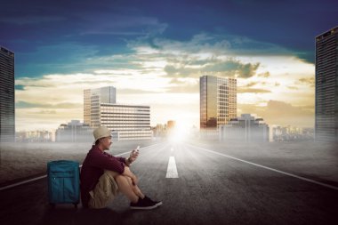 Cep telefonu ile oynarken yolda oturan adam