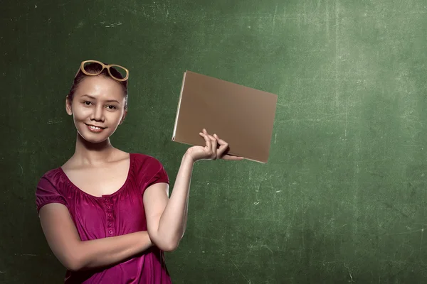 Vrouwelijke student holding boek met schoolbord achtergrond — Stockfoto