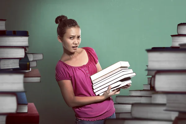 Estudiante femenina lleva muchos libros — Foto de Stock