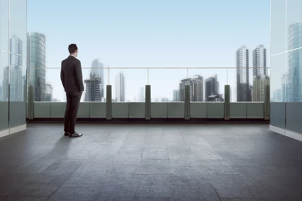 Uomo d'affari in piedi su un tetto e guardando la città — Foto Stock