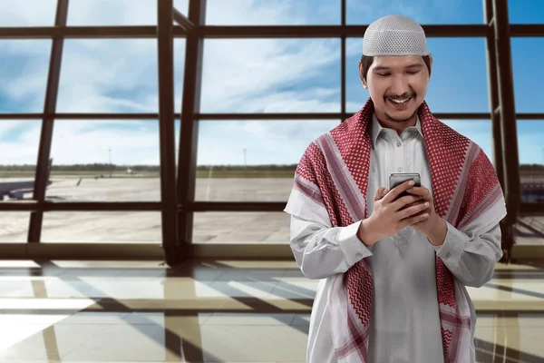 Muslimsk man håller mobiltelefon i flygplats — Stockfoto
