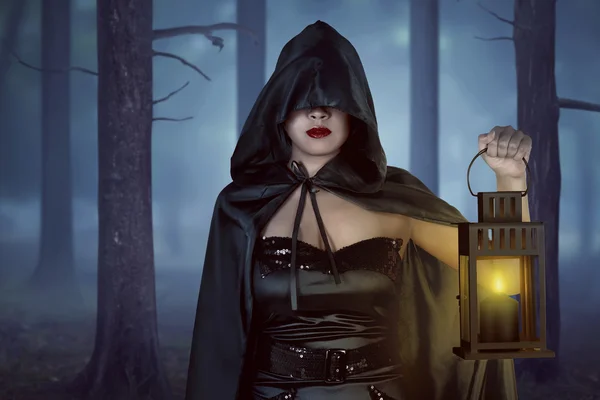 Witch woman holding lantern in forest — Stock Photo, Image