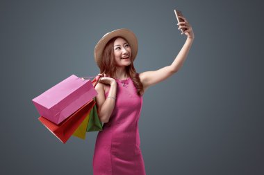 Şapka ve parlak kıyafetleri alışveriş torbaları selfie alarak ile neşeli Asyalı kadın portreleri