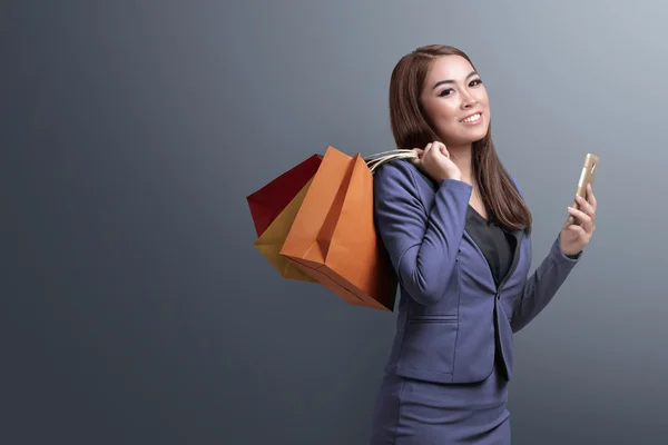 Vásárlás ideje, ázsiai nő smartphone gazdaság bevásárló táskák — Stock Fotó