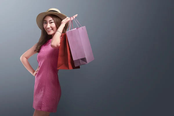 Mujer asiática feliz con sombrero sosteniendo bolsas de compras —  Fotos de Stock