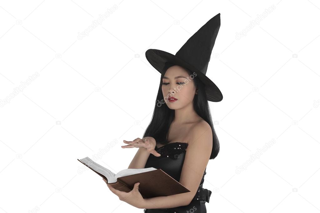 Asian witch creating spell at book