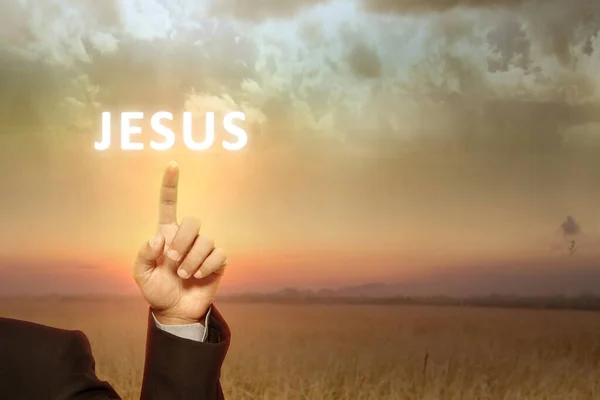 商人的手显示耶稣的文字与日出的天空背景 — 图库照片