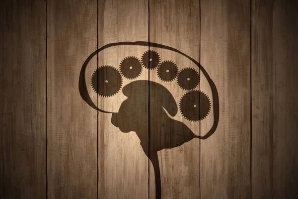 Gear wheels in the human brain on wooden background