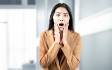 Ofis odasında şok olmuş bir ifadeyle Asyalı iş kadını.