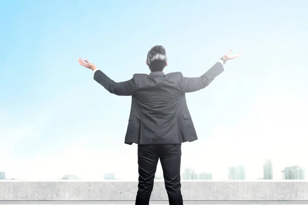 青い空を背景に 屋上で手を上げて立つアジア人ビジネスマンの後ろ姿 — ストック写真