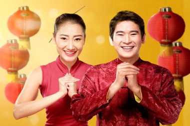 Cheongsam elbiseli Asyalı Çinli çift tebrik jesti yapıyor. Mutlu Çin Yeni Yılı
